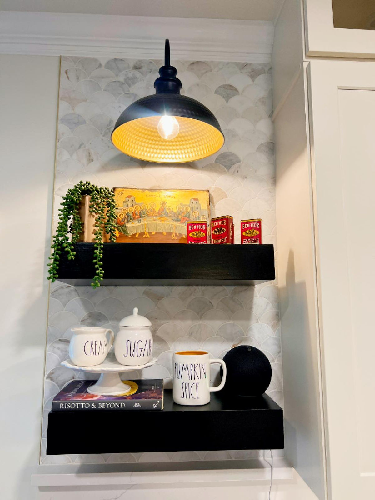 Black shelves with a lit pendant light display mugs labeled 