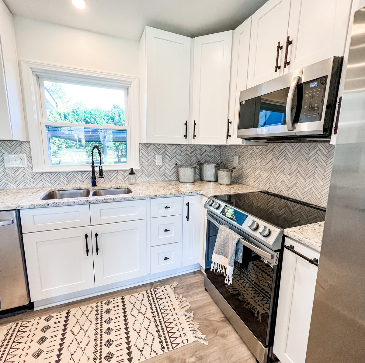 renovation of small kitchen with stainless steel appliances, light wood floors, and white cabinetry