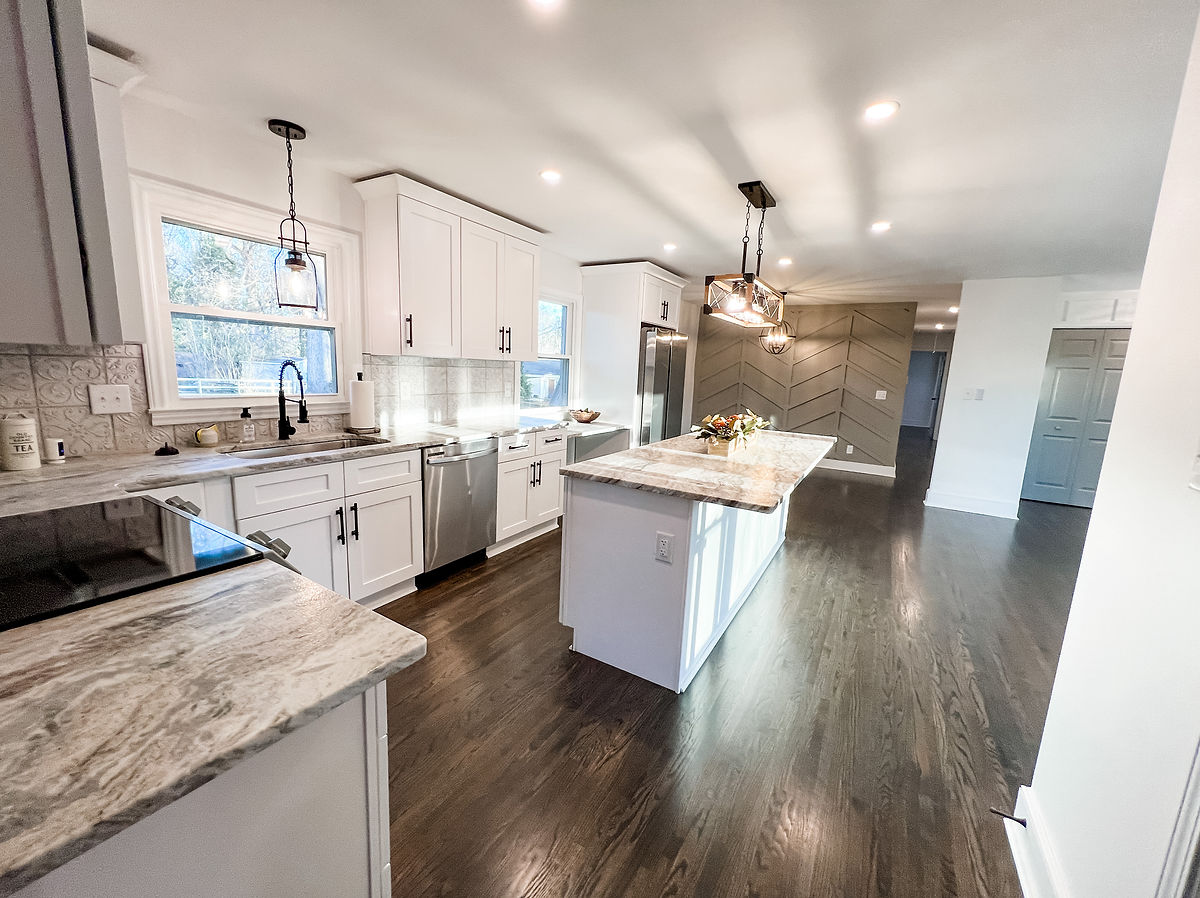 kitchen renovation featuring gray herringbone accent wall, white cabinetry, gray granite counters, and stainless steel appliances