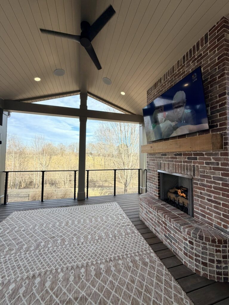 home renovation near Huntersville, NC featuring covered porch open to a wooded area with a brick fireplace to the right