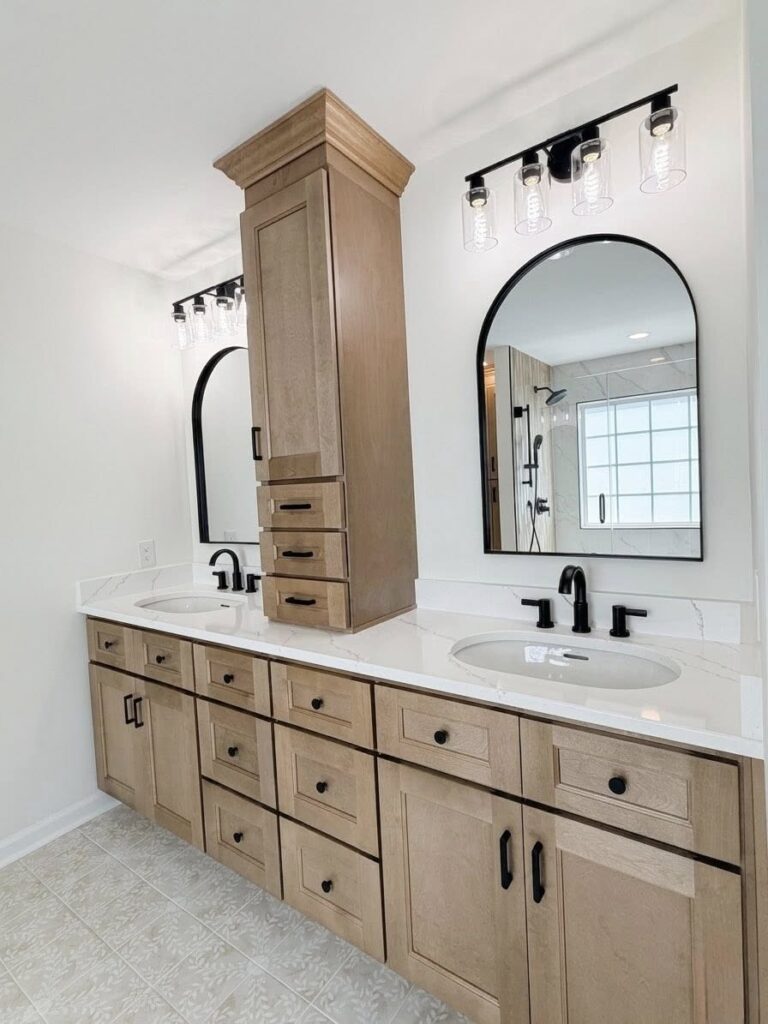 Bathroom home renovation near Cornelius, NC featuring bright white walls, light wood cabinetry, and black fixtures and hardware