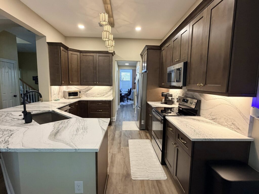 kitchen renovation near Davidson NC featuring dramatic stone counters, dark wood cabinetry, and stainless steel appliances.