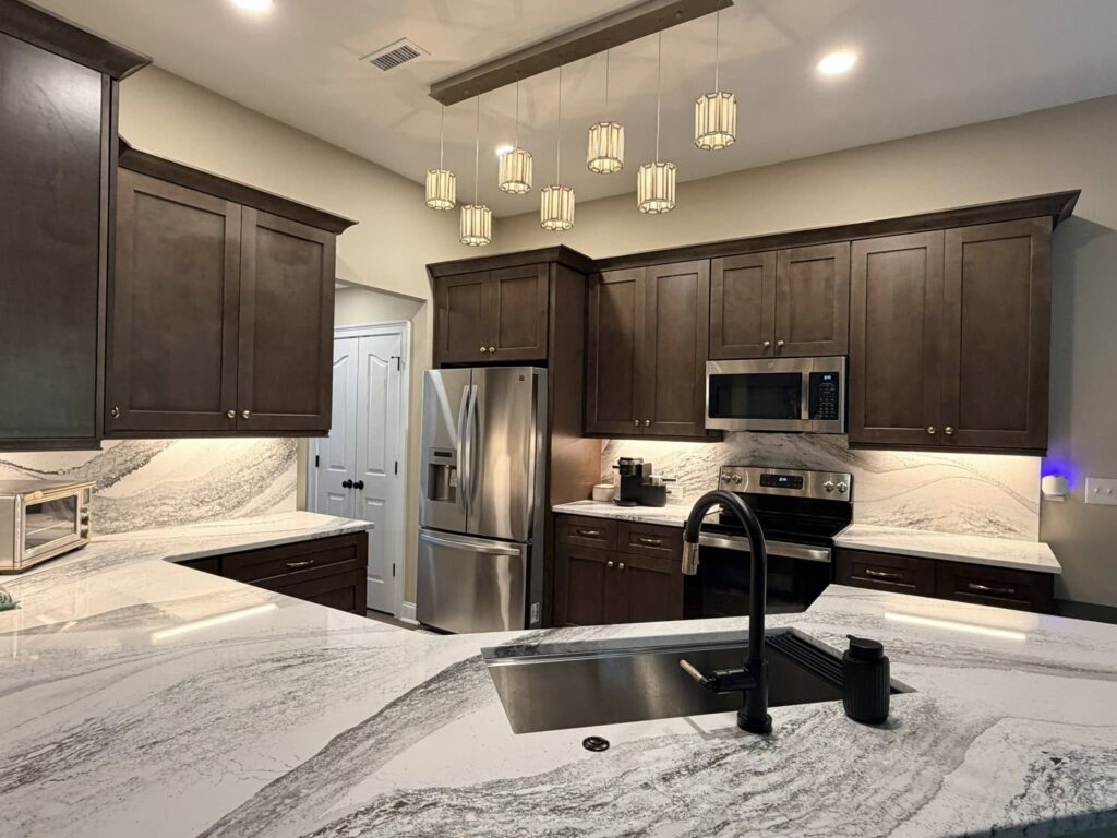 kitchen with dark wood cabinetry, stainless appliances, and stone counters and backsplash.