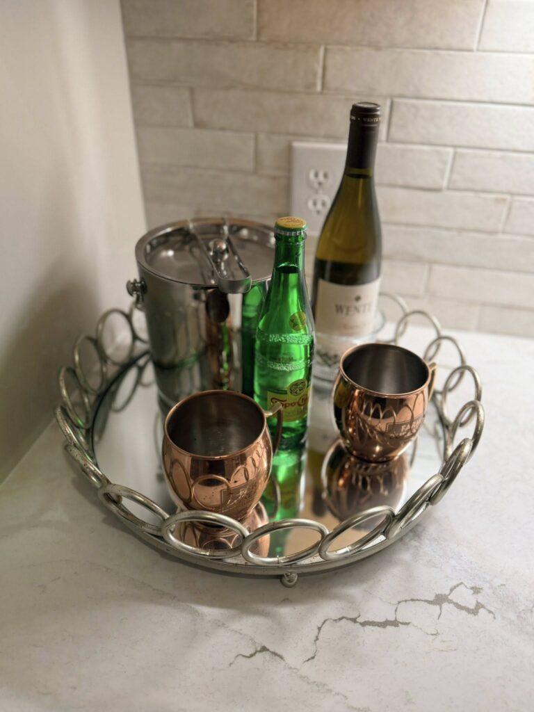 a silver tray holds cups, drinks, and an ice bucket on stone counters, in front of a brick backsplash in a finished home renovation near Cornelius, NC.
