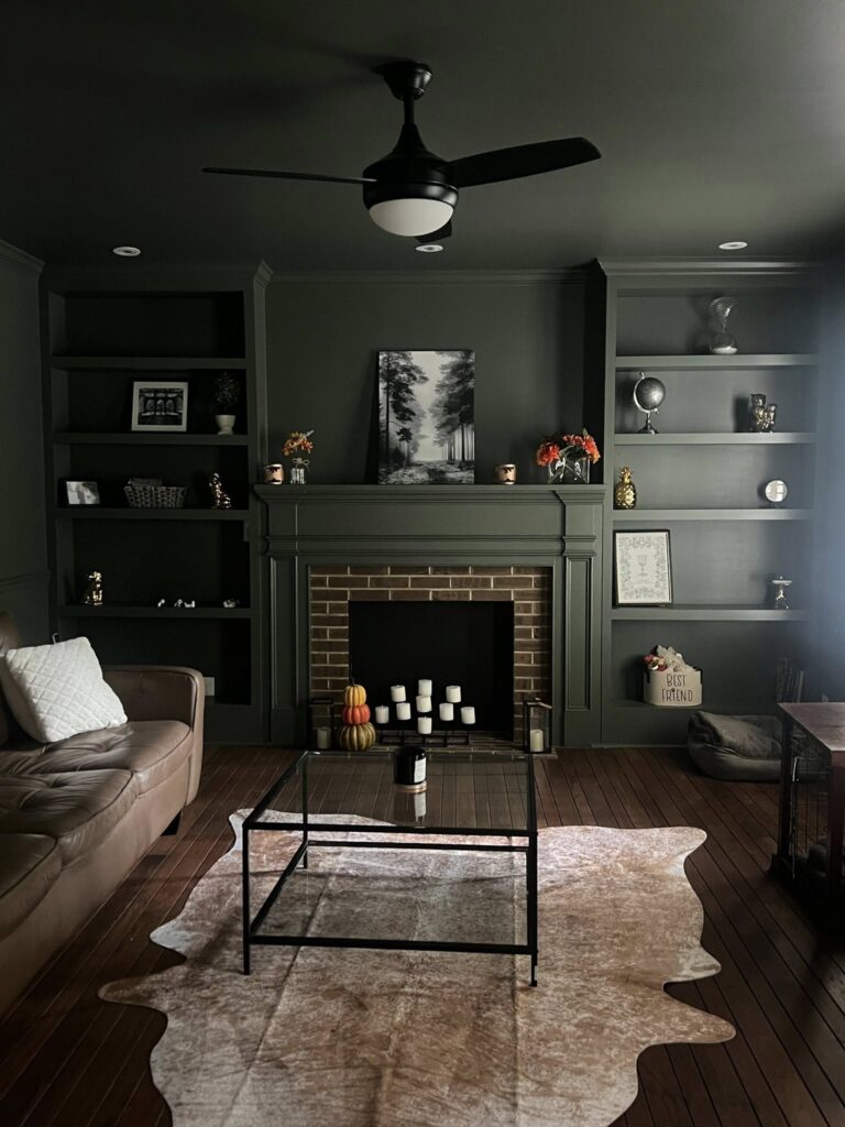 custom home renovation near Davidson NC featuring color drenched dark green built ins surrounding a brick fireplace open to a living room