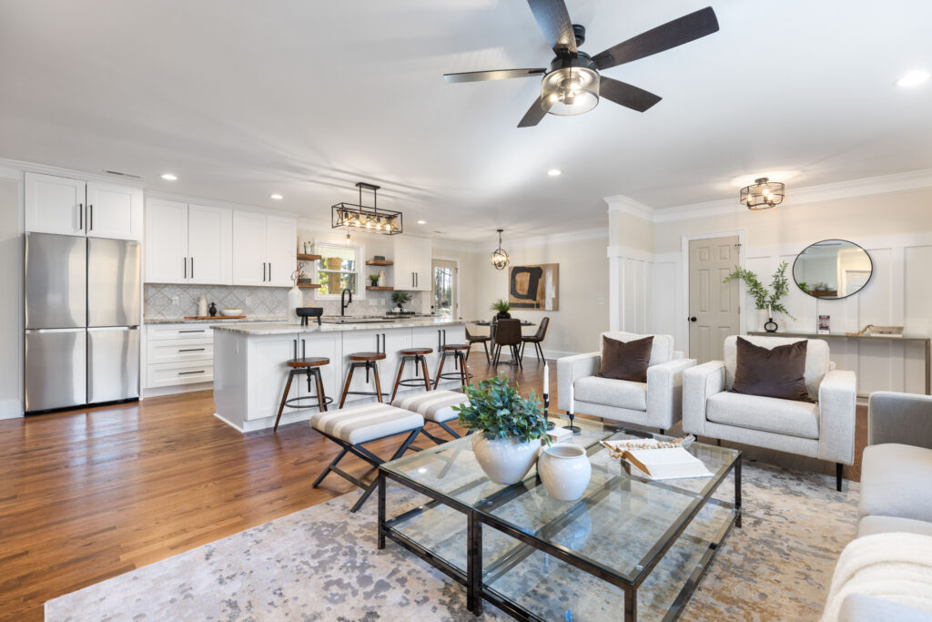 weekend living space near cornelius NC featuring fresh off white walls, large sitting area with cream chairs and benches, large stone topped island with wood barstools in front of a white kitchen