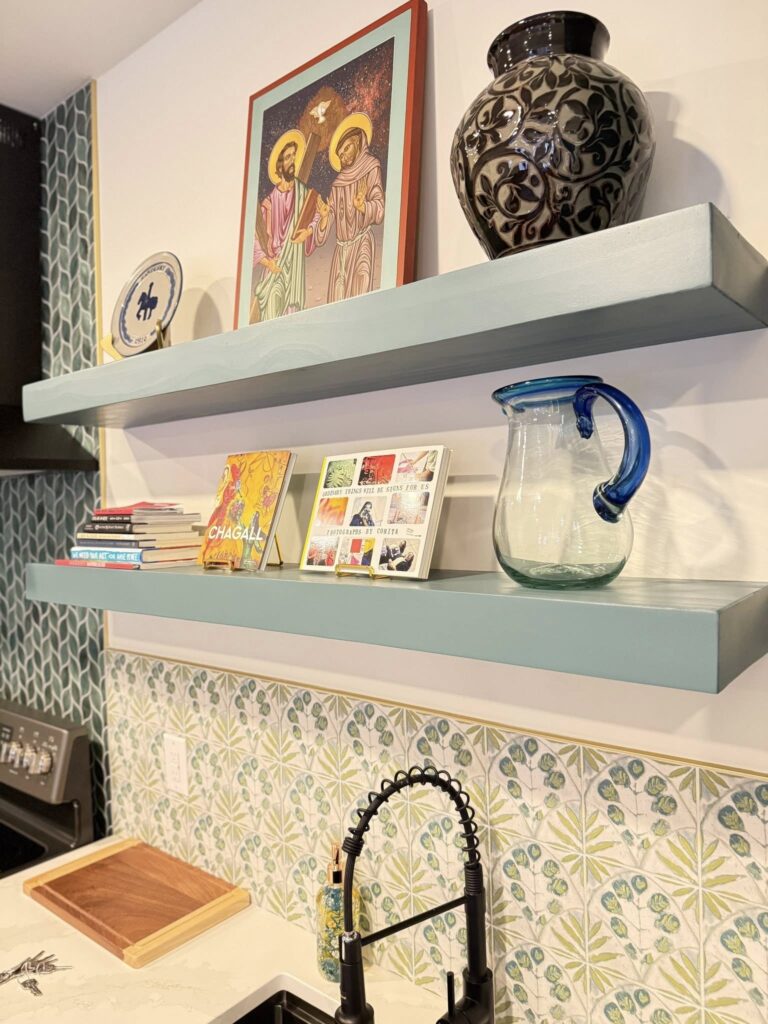 Art studio renovation featuring open shelving with art displayed above a practical black sink with extendable sprayer head.