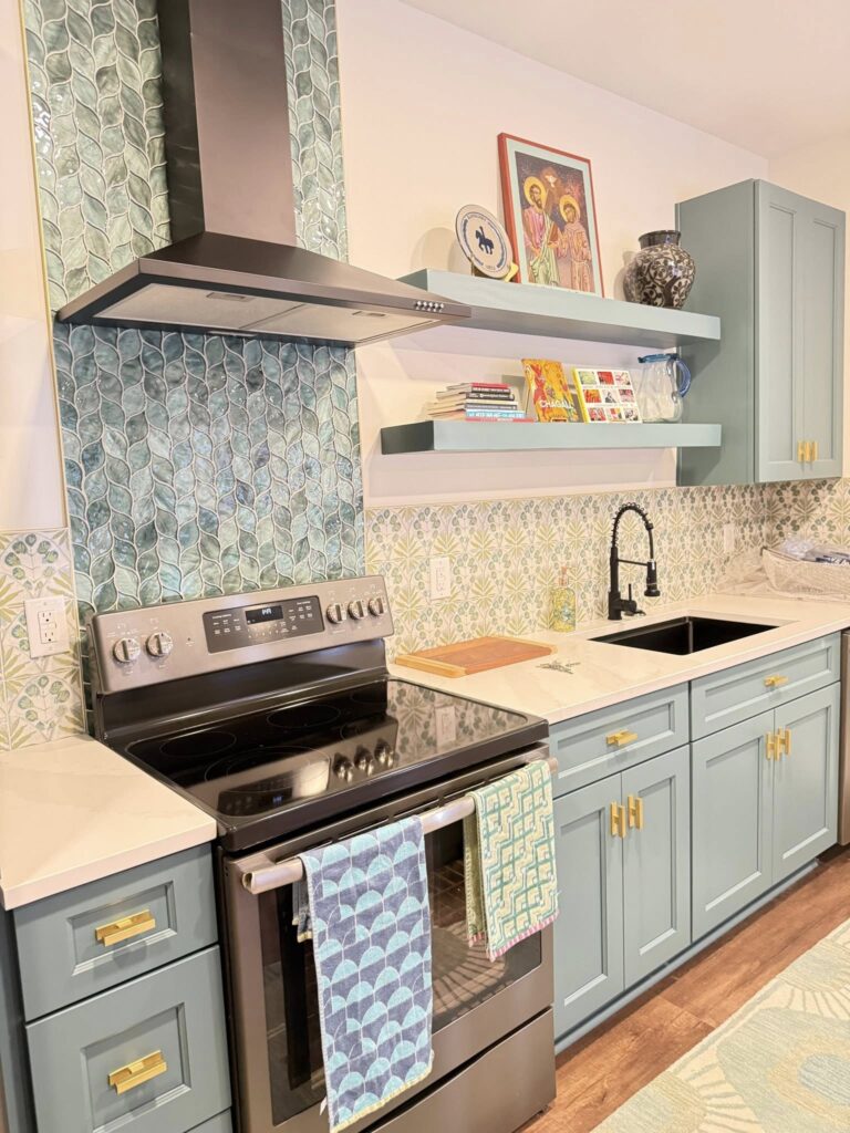 A kitchen renovation featuring intentional design. Practical necessities like the stove and sink are balanced with upgrades like beautiful painted tile, and light blue cabinetry.
