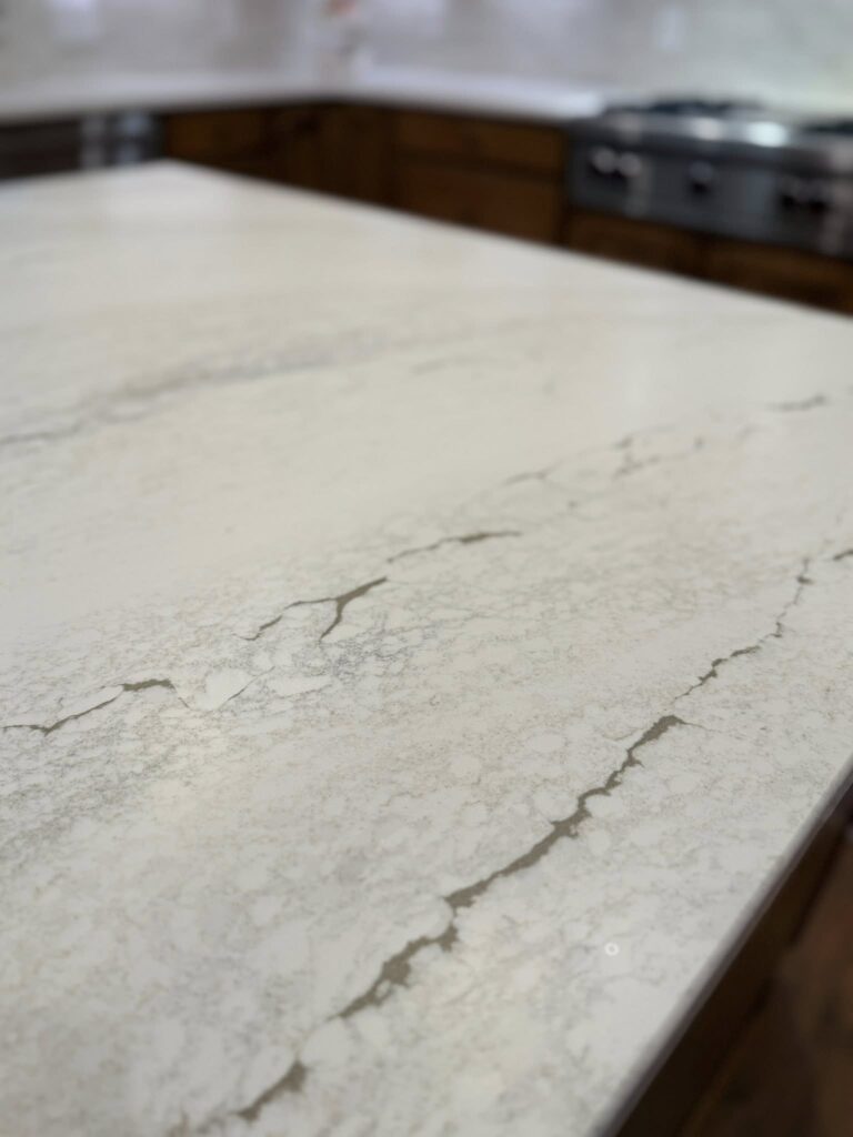Close up on light colored stone kitchen countertop with gray veining dispersed throughout.