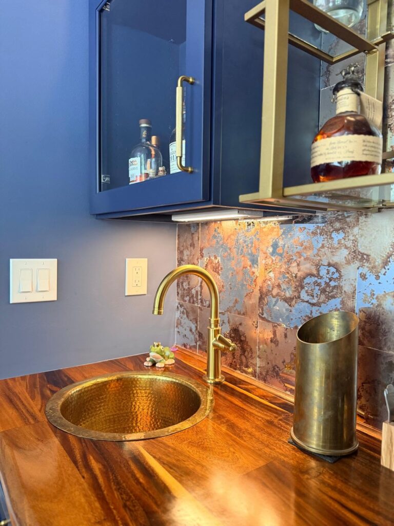 Hammered gold sink in the bar of this custom home renovation. unique aged metal backsplash tile and wooden countertop complete the high end vibe
