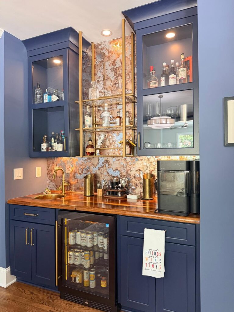 Timeless home design featured in a renovated bar with blue cabinetry, gold hardware, and a metallic patina inspired backsplash.