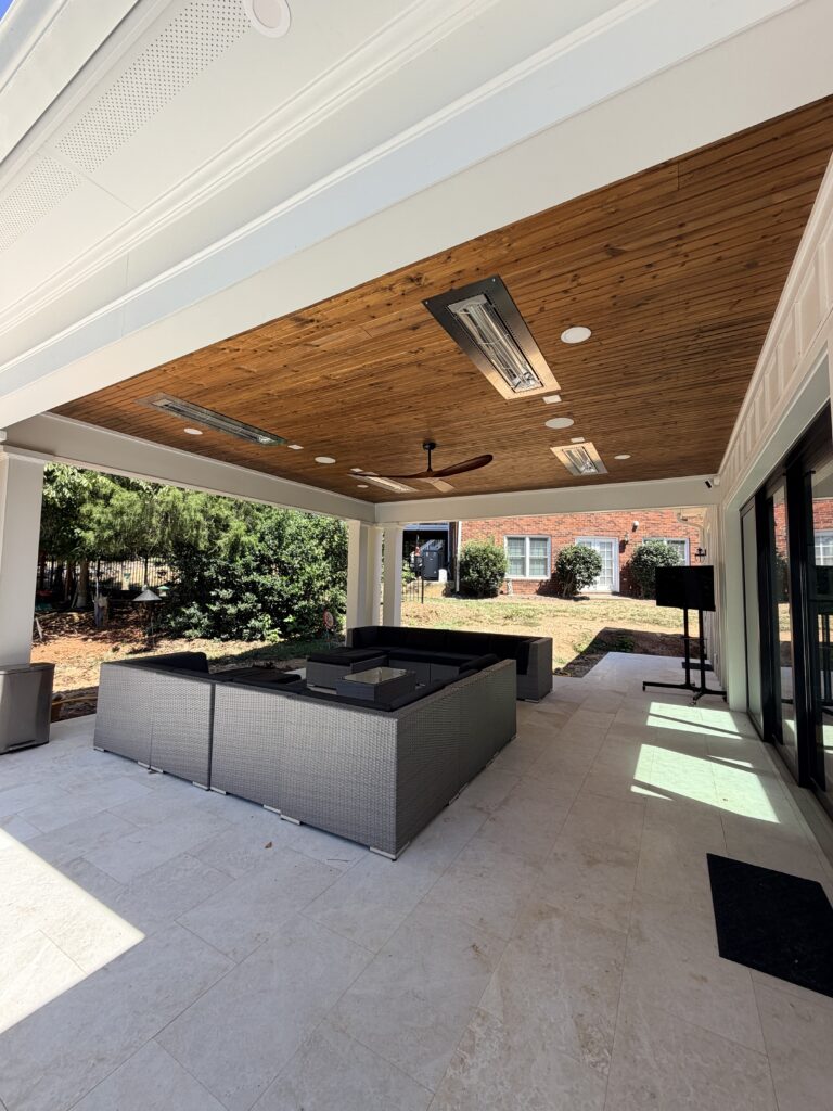 luxury home renovation near Huntersville, NC showcasing huge patio area with seating, ceiling fan, and heaters hidden in wood ceiling above.