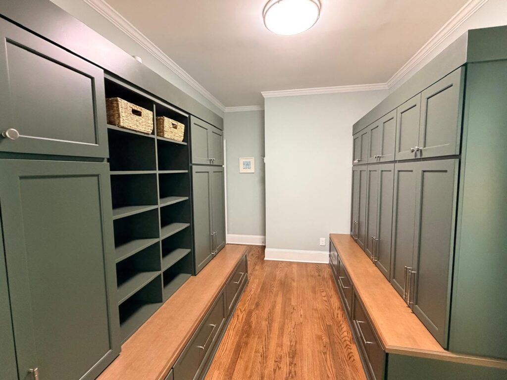 Luxury home remodel near davidson, NC featuring huge mudroom with dark green cabinets and shelving on two walls with wooden benches in front and drawers underneath